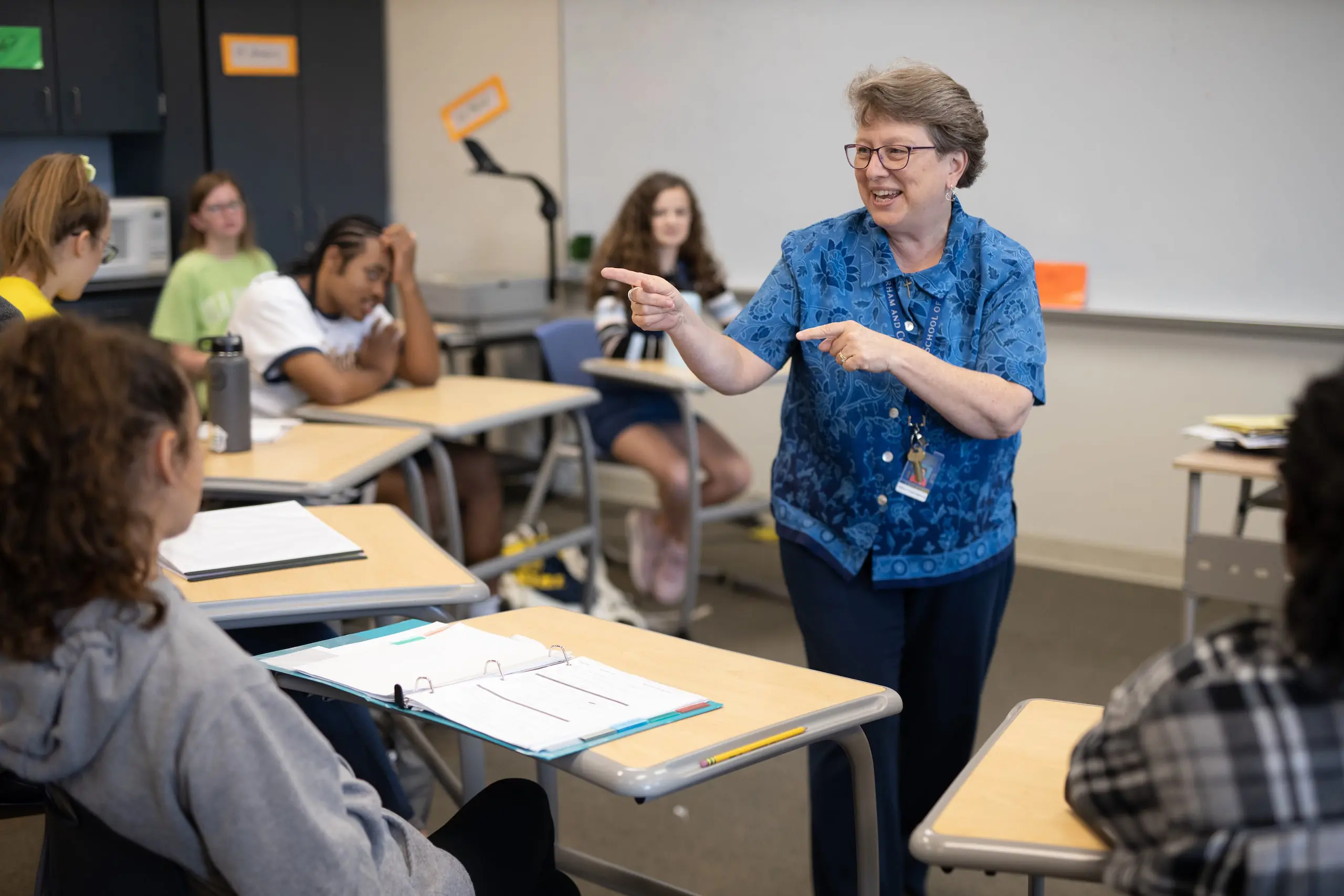 Trinity member of staff joyfully engaged in teaching students in the classroom