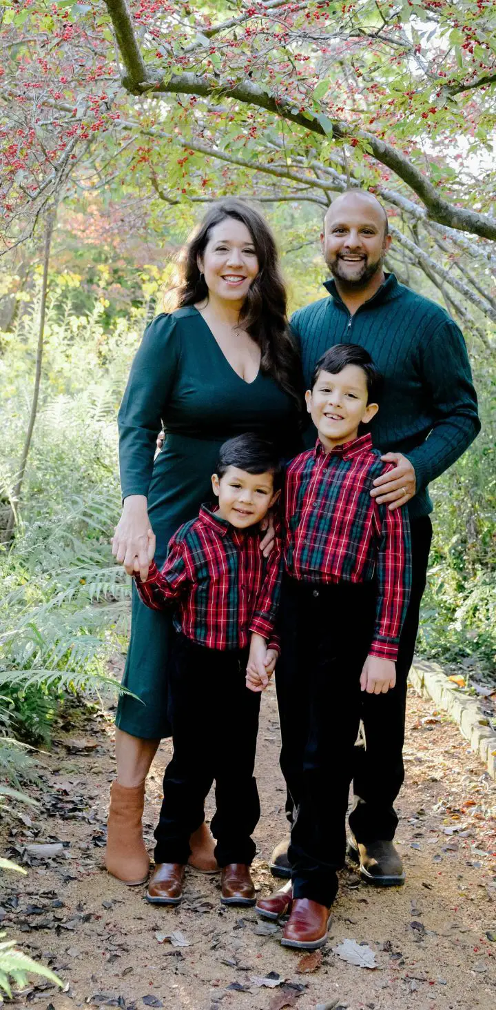 A happy family posing for a portrait in an autumn setting, with two smiling children and cheerful parents.