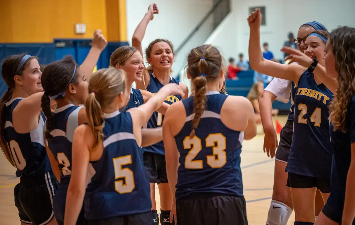 Trinity Lower School female basketball team celebrating victory on court