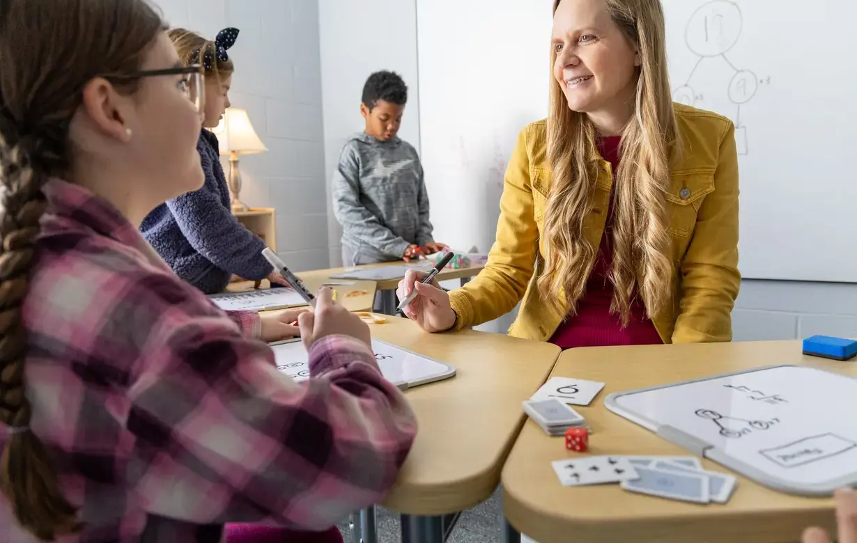 Interactive math lesson in a Trinity School Lower School classroom with a teacher engaging students using visual aids and hands-on materials, highlighting the school's supportive learning environment.