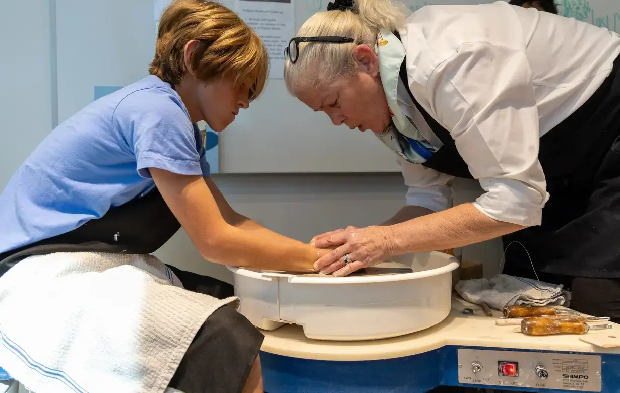 Teacher and student making clay pot