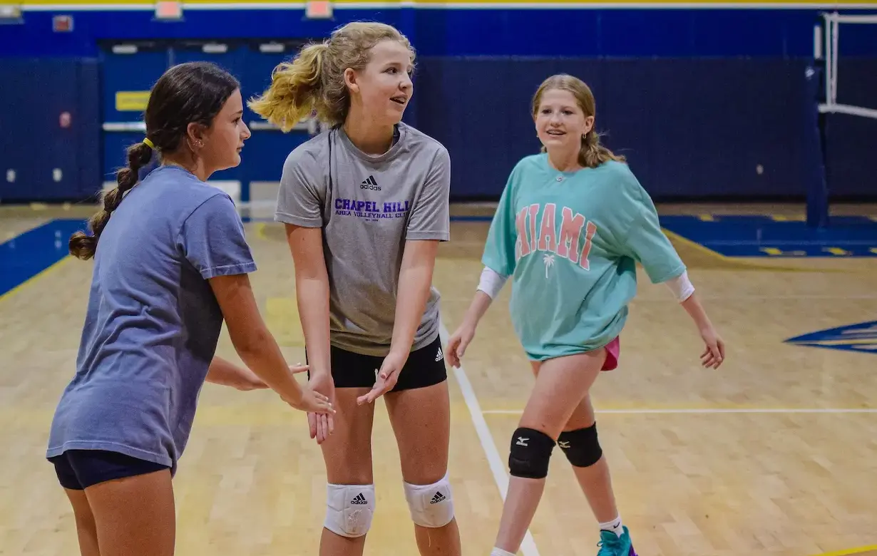 Three female students are on a basketball court 