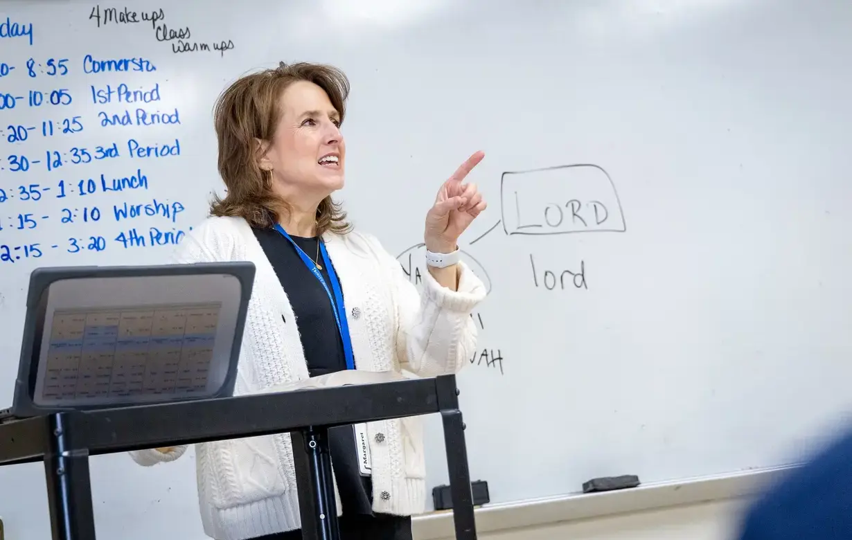 Teacher standing in front of whiteboard explaining to the class